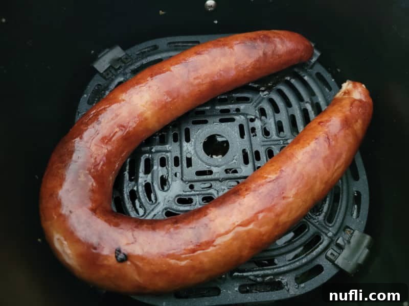 Perfectly air fried kielbasa, golden brown and ready to eat, in an air fryer basket.