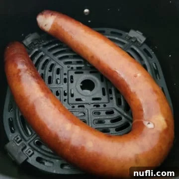 Air fried kielbasa in an air fryer basket, ready to be served.