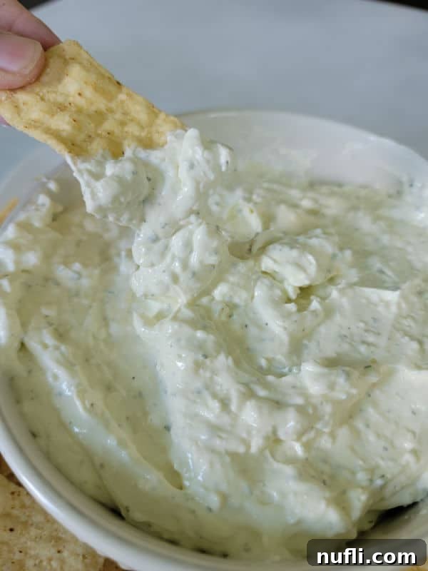 Simple 3-Ingredient Creamy Hidden Valley Ranch Dip 7 Tortilla chip dipping into ranch dip in a white bowl