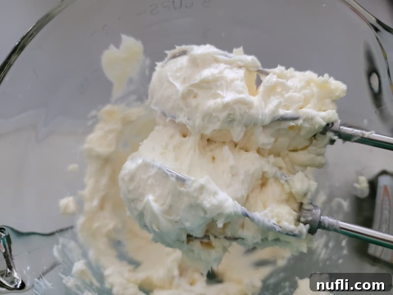 creamed cream cheese on hand mixer beaters in a glass bowl for chocolate chip cream cheese ball