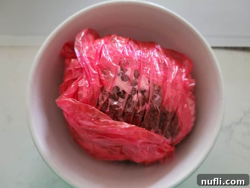 red plastic wrap around a chocolate chip cheese ball in a white bowl