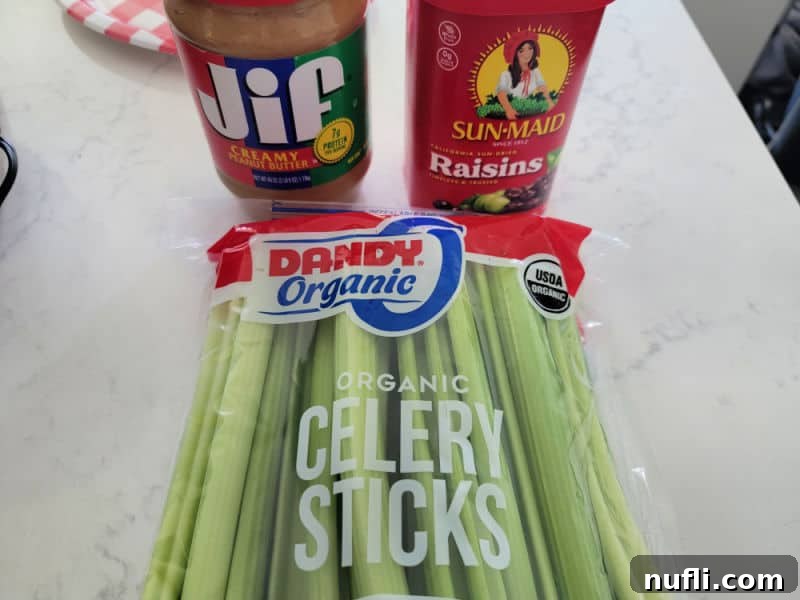 Essential ingredients for Ants on a Log: Jif Peanut Butter, Sun-Maid Raisins, and fresh celery sticks neatly arranged on a white kitchen counter, ready for preparation