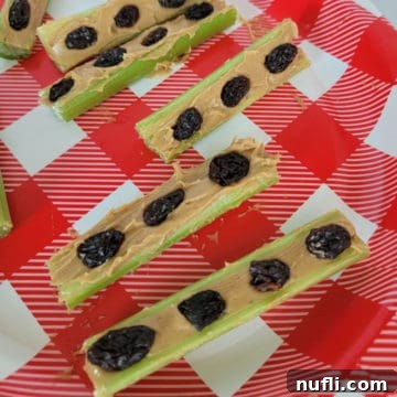 Ants on a Log with peanut butter, raisin, and celery on a red and white plate