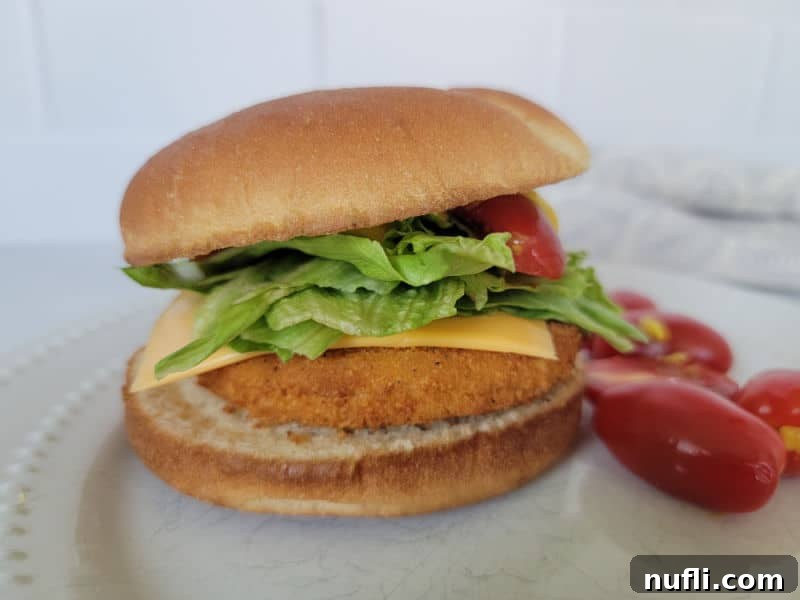 air fried chicken burger on a bun with lettuce, tomato, and cheese