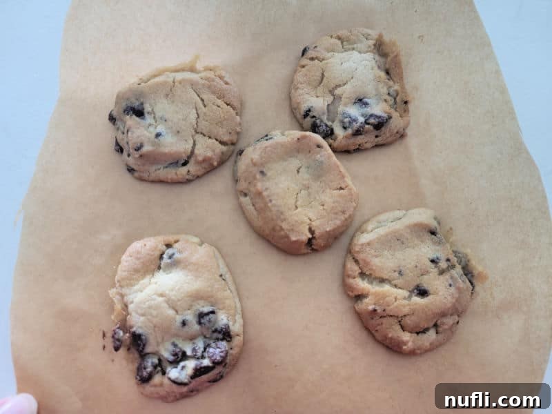 Air Fryer Cookie Delights 6 Beautifully baked chocolate chip cookies on parchment paper, showcasing the perfect texture and golden color achievable with an air fryer.