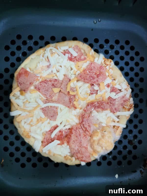 Frozen personal pepperoni pizza placed inside an air fryer basket