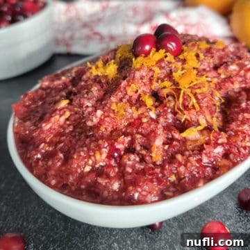 Cranberry Orange Relish in a white bowl garnished with citrus zest and cranberries