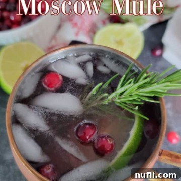 cranberry mule in a copper mug with cranberries and rosemary garnish
