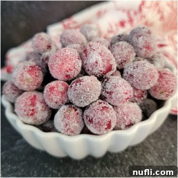 Sugared Cranberries in a white bowl with a red and white towel