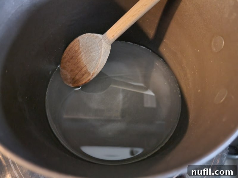 Clear simple syrup in a saucepan, ready for cranberries to be added for candied cranberries