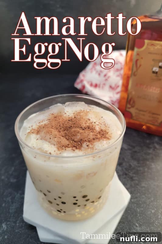 Simple Amaretto Eggnog Cocktail 2 A festive Amaretto Eggnog cocktail, beautifully garnished with ground nutmeg, next to a bottle of Amaretto. The scene evokes holiday warmth and easy elegance.