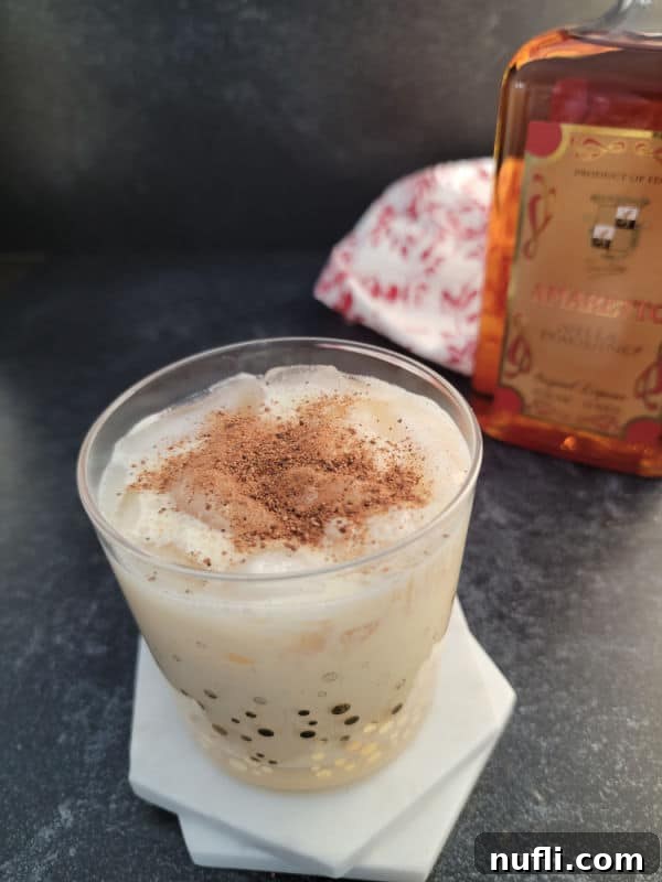 Simple Amaretto Eggnog Cocktail 5 A festive Amaretto Eggnog cocktail in a clear glass, with a luxurious sprinkle of ground nutmeg, ready to be enjoyed during the holidays.