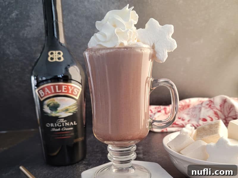 Effortless Baileys Hot Chocolate 5 Bailey's Irish Cream Hot Chocolate in a glass mug with whipped cream and a star marshmallow next to a bottle of Baileys Irish cream