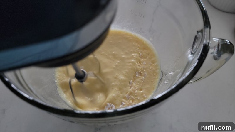 electric hand mixer mixing eggnog pie ingredients in a glass bowl