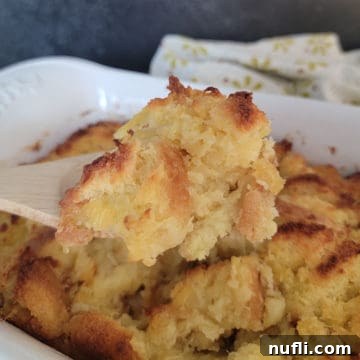 Effortless 5 Ingredient Pineapple Stuffing 12 Pineapple Stuffing on a wooden spoon above a white casserole dish