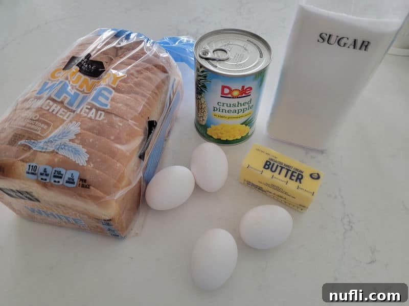 Effortless 5 Ingredient Pineapple Stuffing 3 Pineapple stuffing ingredients, white bread, eggs, pineapple juice, butter, sugar on a white quartz counter