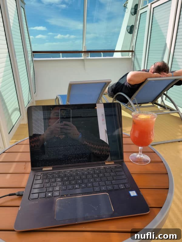 Tammilee taking a photo of a laptop next to a tropical drink with john lounging on a lounge chair with the ocean in the distance