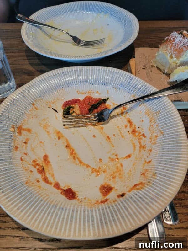 Empty plate with remnants of tomato sauce and a fork