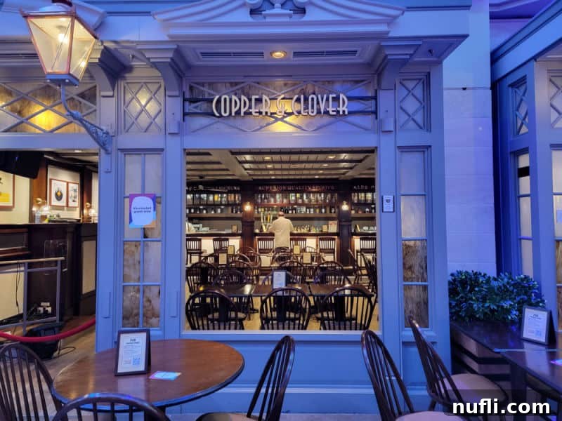 Cooper & Clover bar entrance with a bartender, tables, and chairs visible through an open window.