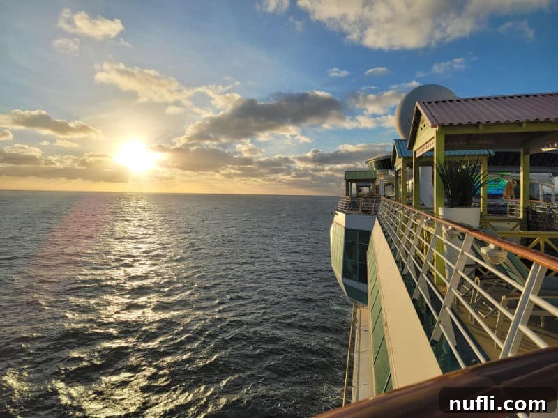 Sunrise in the distance over the ocean, with the side of a cruise ship visible in the foreground