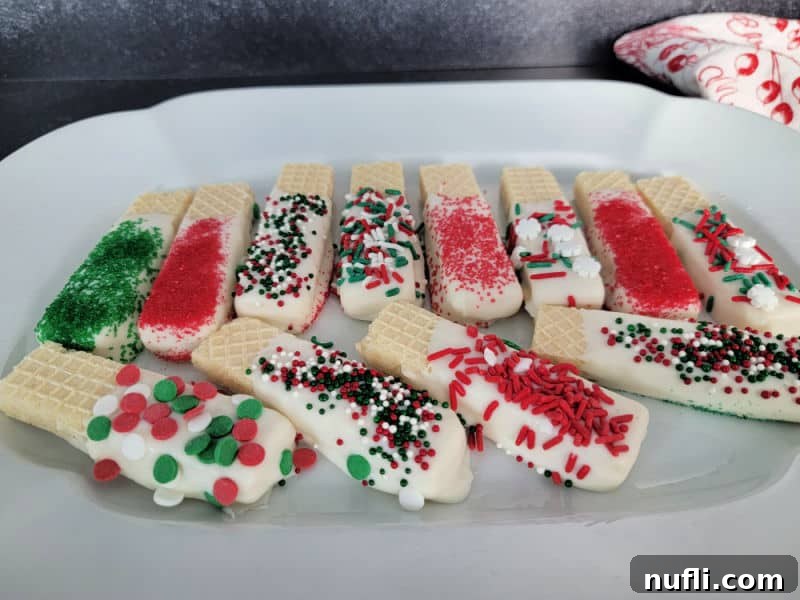 White chocolate dipped wafers coated in holiday sprinkles arranged neatly on a platter