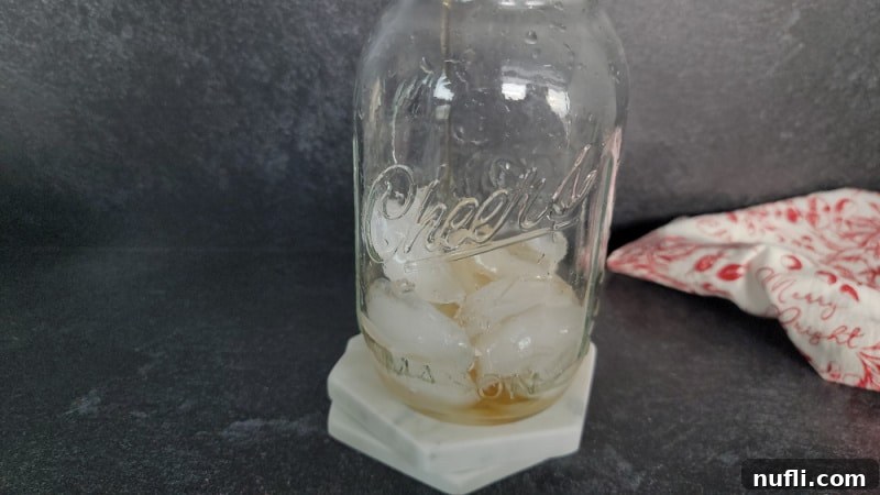 Crimson Capture 4 Clear mason jar with ice and liquid in it sitting on two white coasters next to a red and white cloth napkin