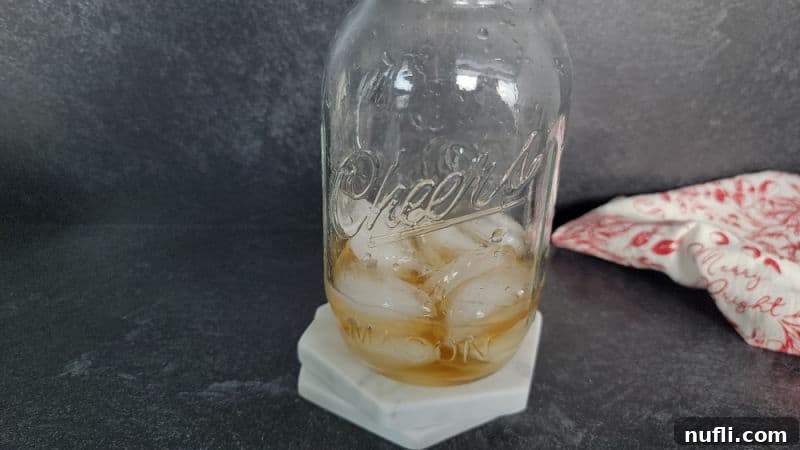Crimson Capture 5 Mason jar filled with ice and liquid on two white coasters next to a red and white cloth napkin