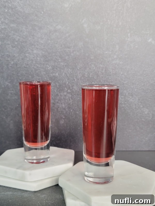 Crimson Capture 9 Two shot glasses filled with red liquid on two white coasters