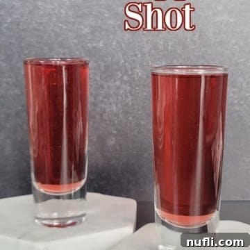 Crimson Capture 10 Red Snapper Shot text over two filled shot glasses on white marble coasters