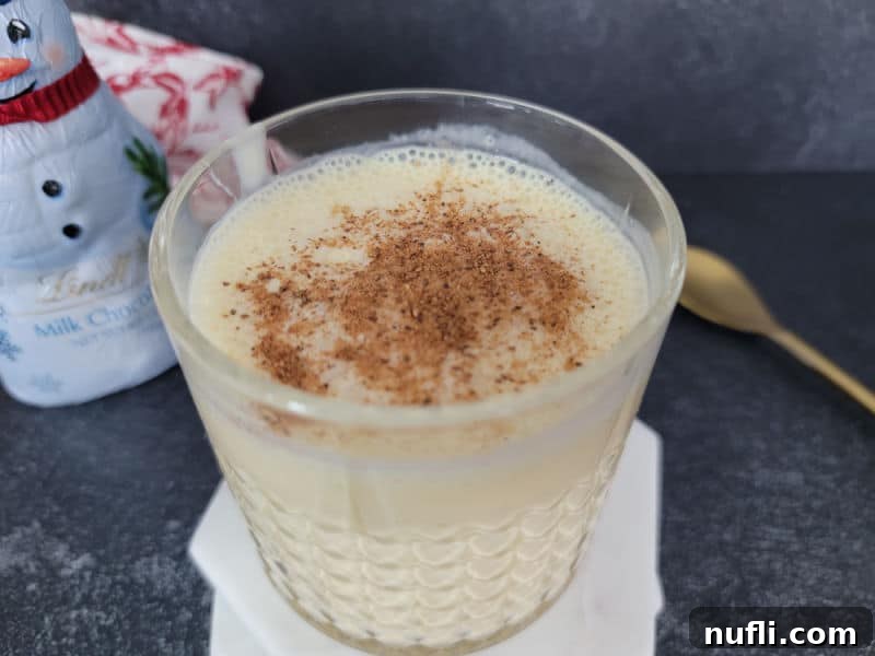 Bourbon eggnog drink garnished with ground nutmeg in a crystal glass