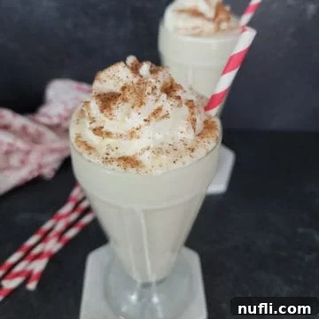Easy Eggnog Shake in a milkshake glass garnished with whipped cream and nutmeg,