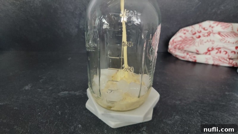 Decadent Eggnog Mudslide 4 Eggnog being poured into a mason jar filled with ice, destined to become an eggnog mudslide cocktail.