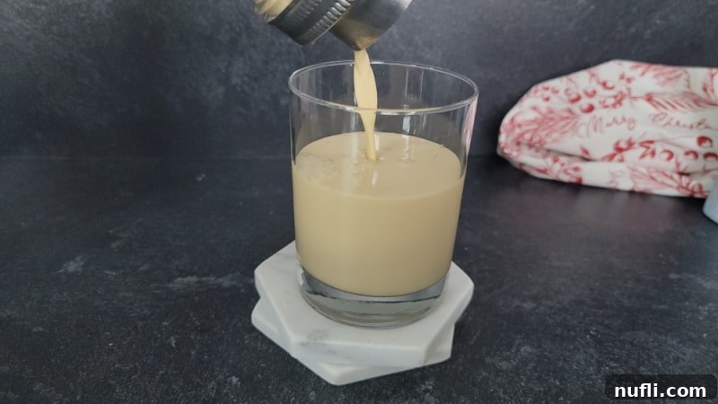 Decadent Eggnog Mudslide 7 The prepared Eggnog Mudslide cocktail being strained from a shaker into a clear old fashioned glass.