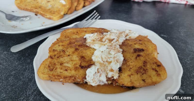 Effortless Eggnog French Toast 13 Eggnog French Toast with Eggnog Whipped Cream on a white plate with a silver fork