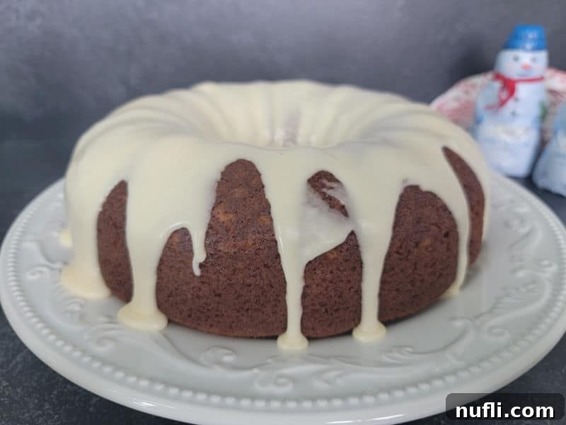 Eggnog glaze dripping over a eggnog bundt cake on a white plate