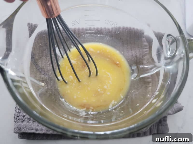 Eggnog glaze ingredients in a clear glass bowl with a whisk