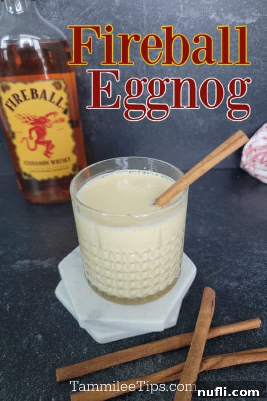 A festive glass of Fireball Eggnog garnished with cinnamon sticks, positioned beside a bottle of Fireball Cinnamon Whisky and a container of classic eggnog, evoking a cozy holiday scene.