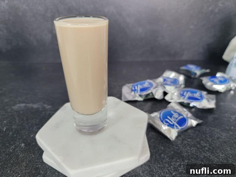Peppermint Patty Shot on white coasters next to peppermint chocolate candy, showcasing its enticing appearance