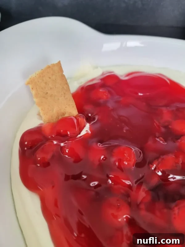 No Bake Cherry cheese cake dip in a white serving bowl with a graham crackers