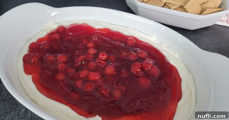 No Bake Cherry cheese cake dip in a white serving bowl with graham crackers