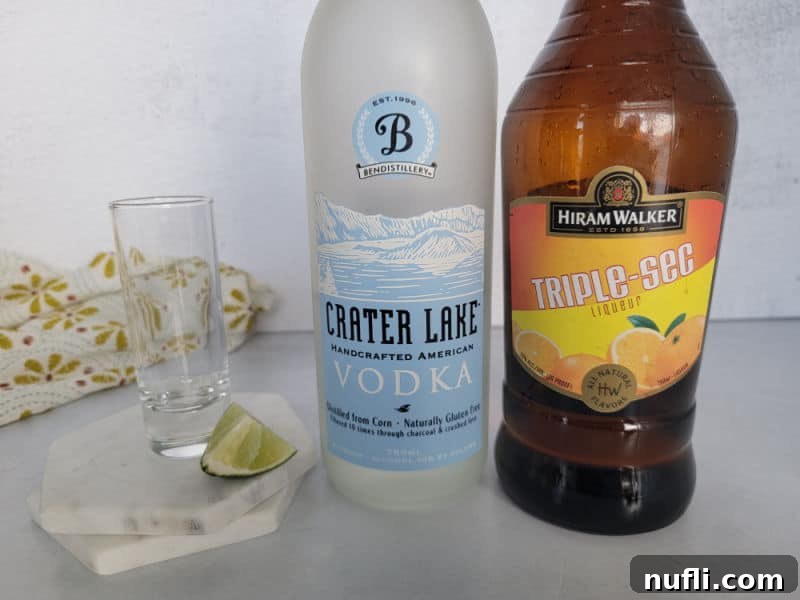 glass shot glass, lime wedge, crater lake vodka, triple sec, and a cloth napkin