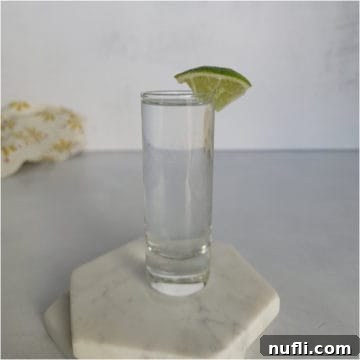 Kamikaze shot in a glass shot glass with lime wedge on white coasters