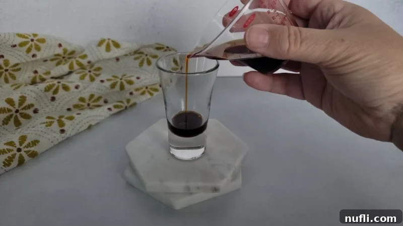 Mastering the Blowjob Shot 4 Hand pouring dark Kahlúa or Amaretto liquid into the bottom of a shot glass.