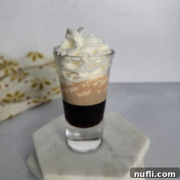 Mastering the Blowjob Shot 8 Blow Job Shot layered in a shot glass on a white coaster, ready to be enjoyed.