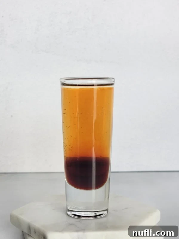 Mind Eraser Shot and Cocktail Creations 4 Layered Mind Eraser shot in a glass shot glass on a coaster