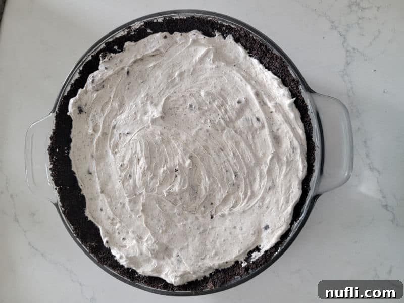 No Bake Oreo Cheesecake spread into a homemade Oreo crust in a glass pie dish
