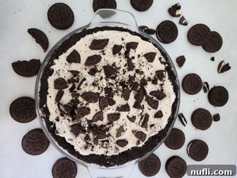 No Bake Oreo cheesecake covered in Oreo crumbs in a glass pie dish