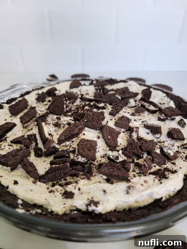 Oreo pieces on top of a No Bake Oreo Cheesecake with an Oreo crumb crust in a glass pie dish