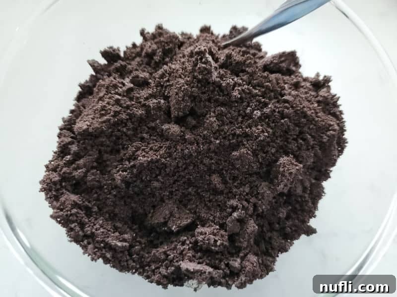 Easy Oreo Pie Crust 5 Crumbled Oreos in a glass bowl with a spoon