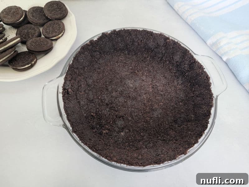 Easy Oreo Pie Crust 7 No Bake Oreo Crust in a pie dish next to a plate of Oreos